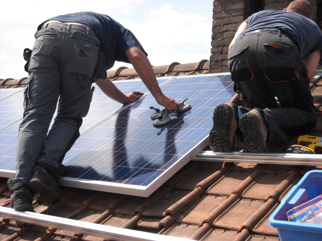 Solar PV panels being installed on the tile roof of a house