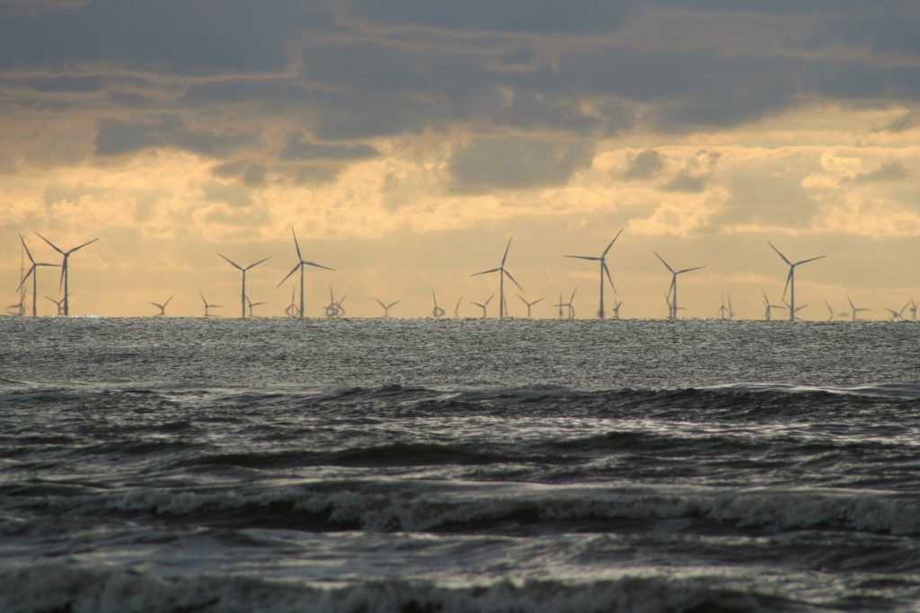 Offshore wind farm on a cloudy day with waves.